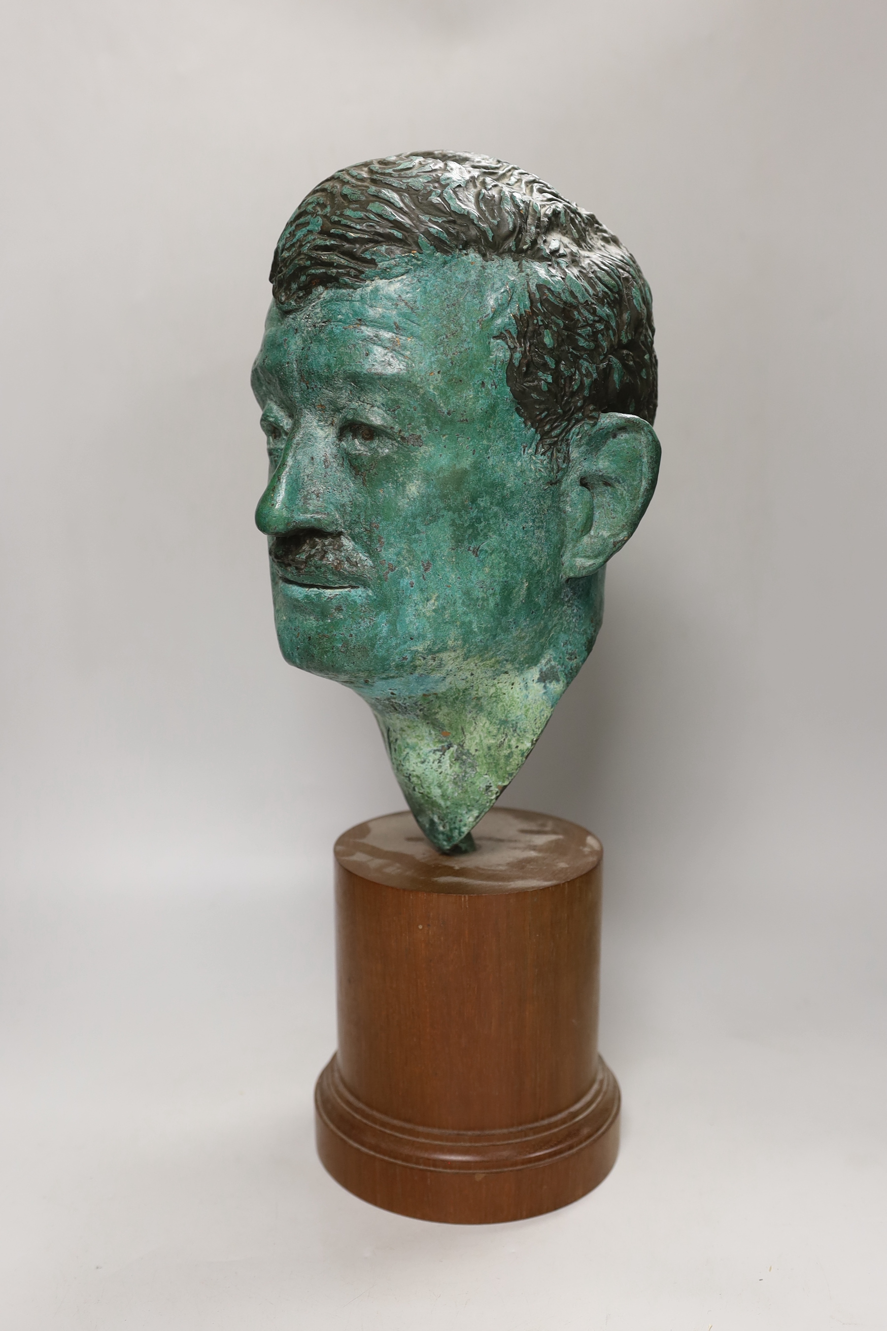 A verdigris metal head of a gentleman mounted on a wooden stand, 48cm high